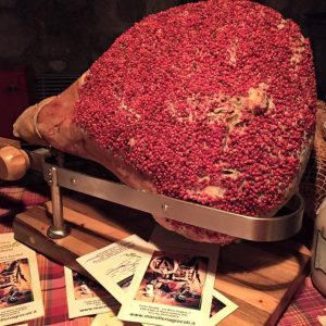Prosciutto crudo appeso in cantina e fette su tagliere